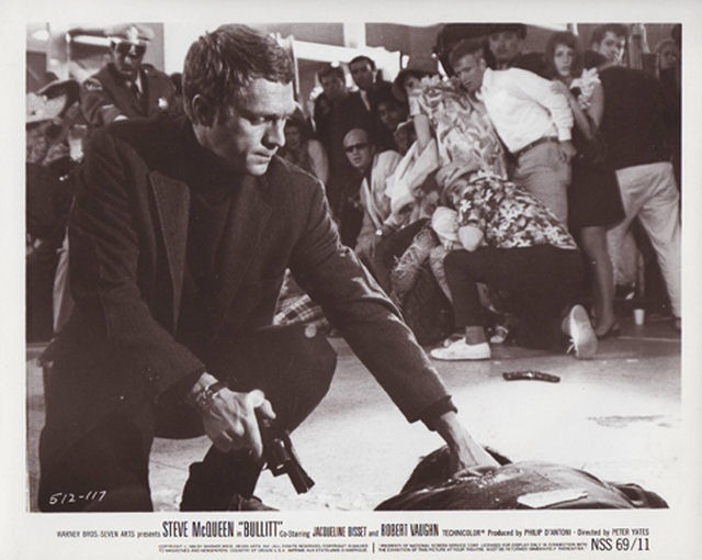 Steve McQueen (as Frank Bullitt) checks the pulse of his adversary after a fatal shootout at the airport.